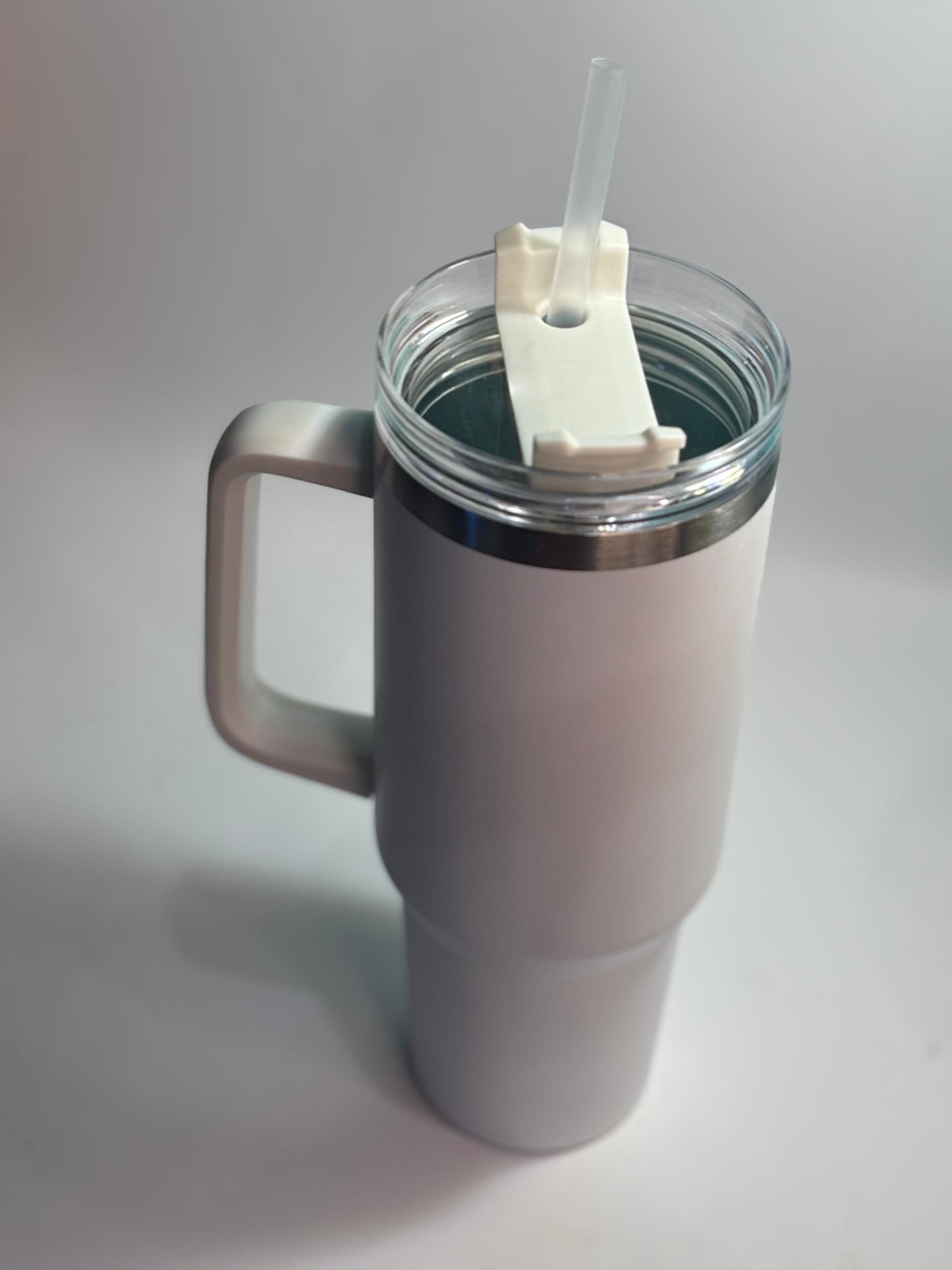 White insulated mug with a straw on a light gray background