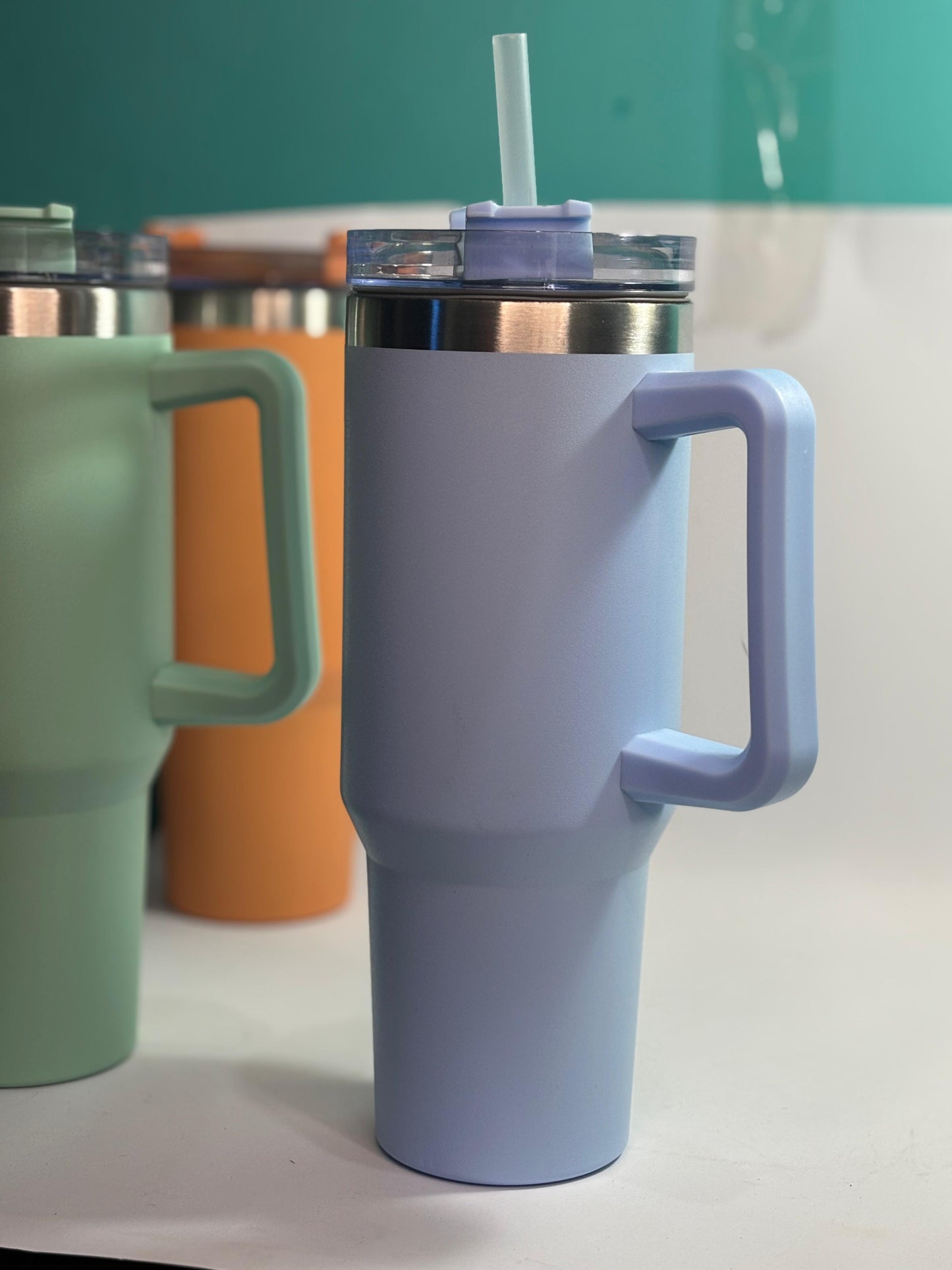 Purple travel mug with handle and straw on a white surface