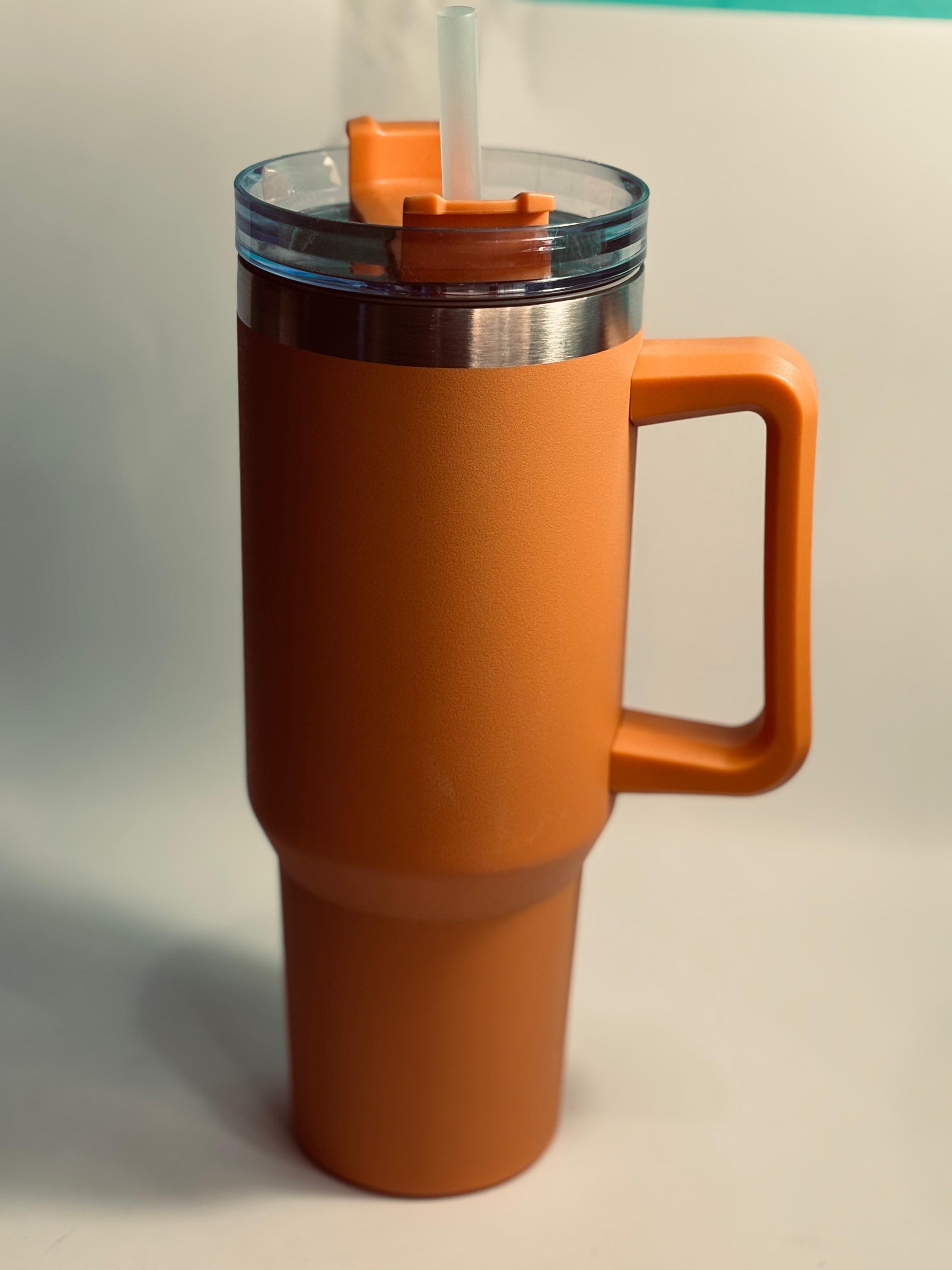 Orange insulated mug with handle and straw on a light gray background 40 oz stainless steel tumbler with straw and handle – leakproof insulated water bottle