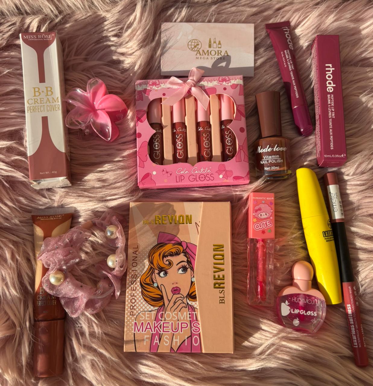 Flat-lay display of assorted beauty products including BB cream, lip gloss sets, mascara, nail polish, lipstick, scrunchies, and a makeup palette arranged on a pink fluffy background.