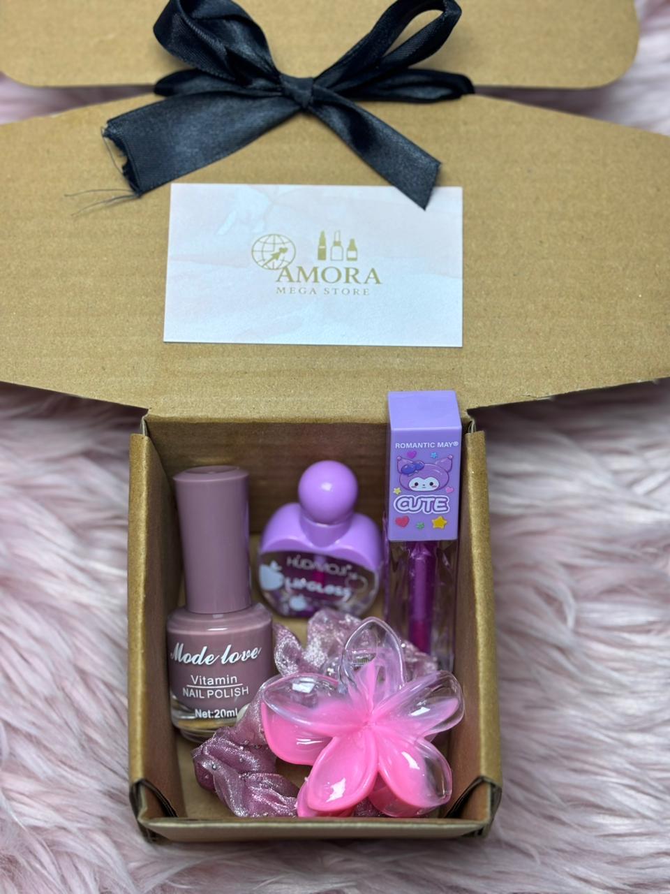 Open kraft gift box containing nail polish, lip gloss, scrunchie, flower clip, and Amora Mega Store card displayed neatly inside.