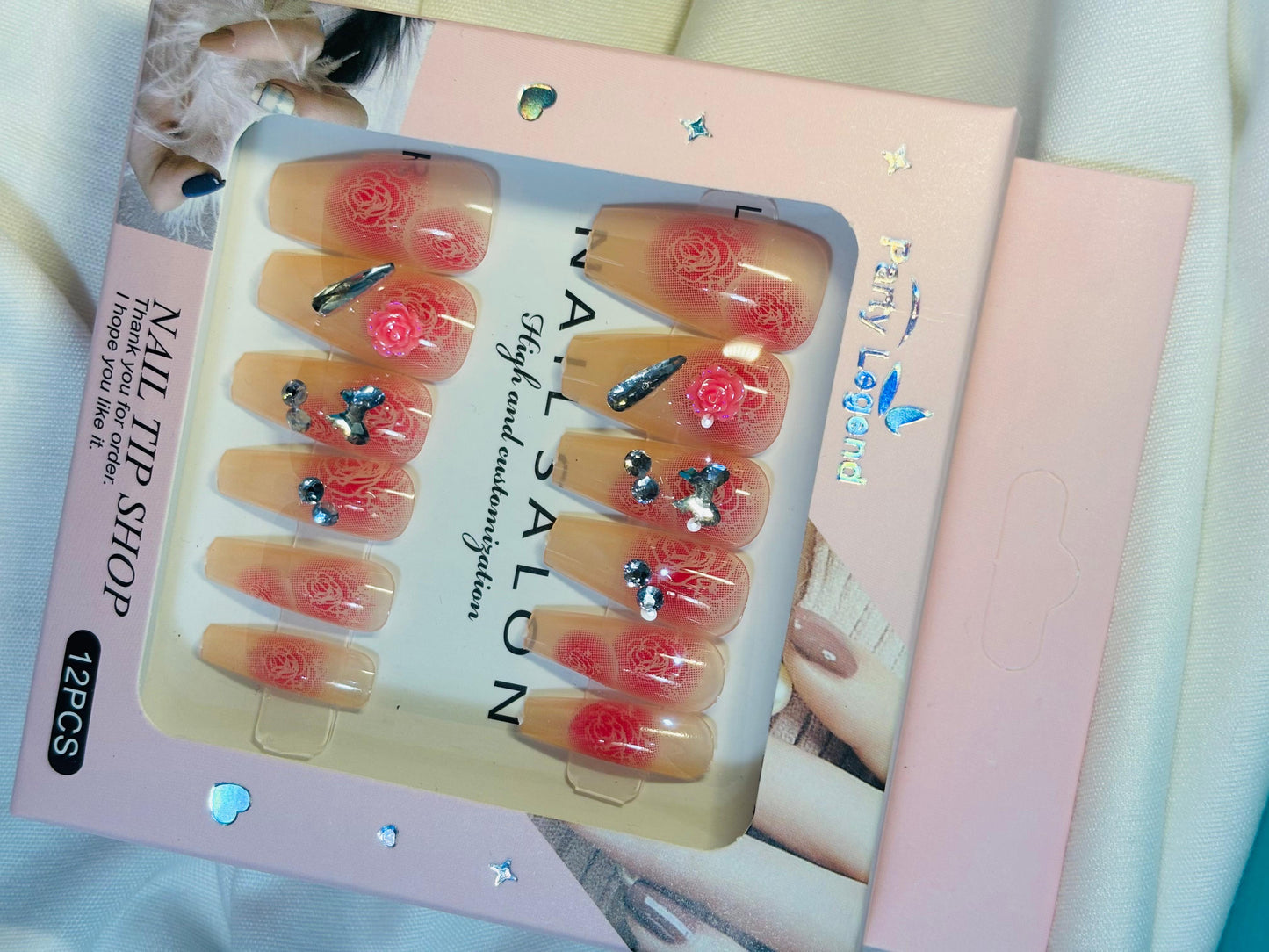 Amora Premium Press-On Fake Nails set box front view

Close-up of press-on nails decorative designs in packaging

Press-on nails box with pink border and branding visible

Display of nail tips floral & rhinestone designs in set

Press-on nails packaging on light background showing full set

Box of artificial nail tips with bold designs close-up

Press-on nail set styled in packaging “Nail Salon” view