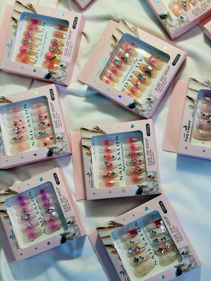 Amora Premium Press-On Fake Nails set box front view

Close-up of press-on nails decorative designs in packaging

Press-on nails box with pink border and branding visible

Display of nail tips floral & rhinestone designs in set

Press-on nails packaging on light background showing full set

Box of artificial nail tips with bold designs close-up

Press-on nail set styled in packaging “Nail Salon” view