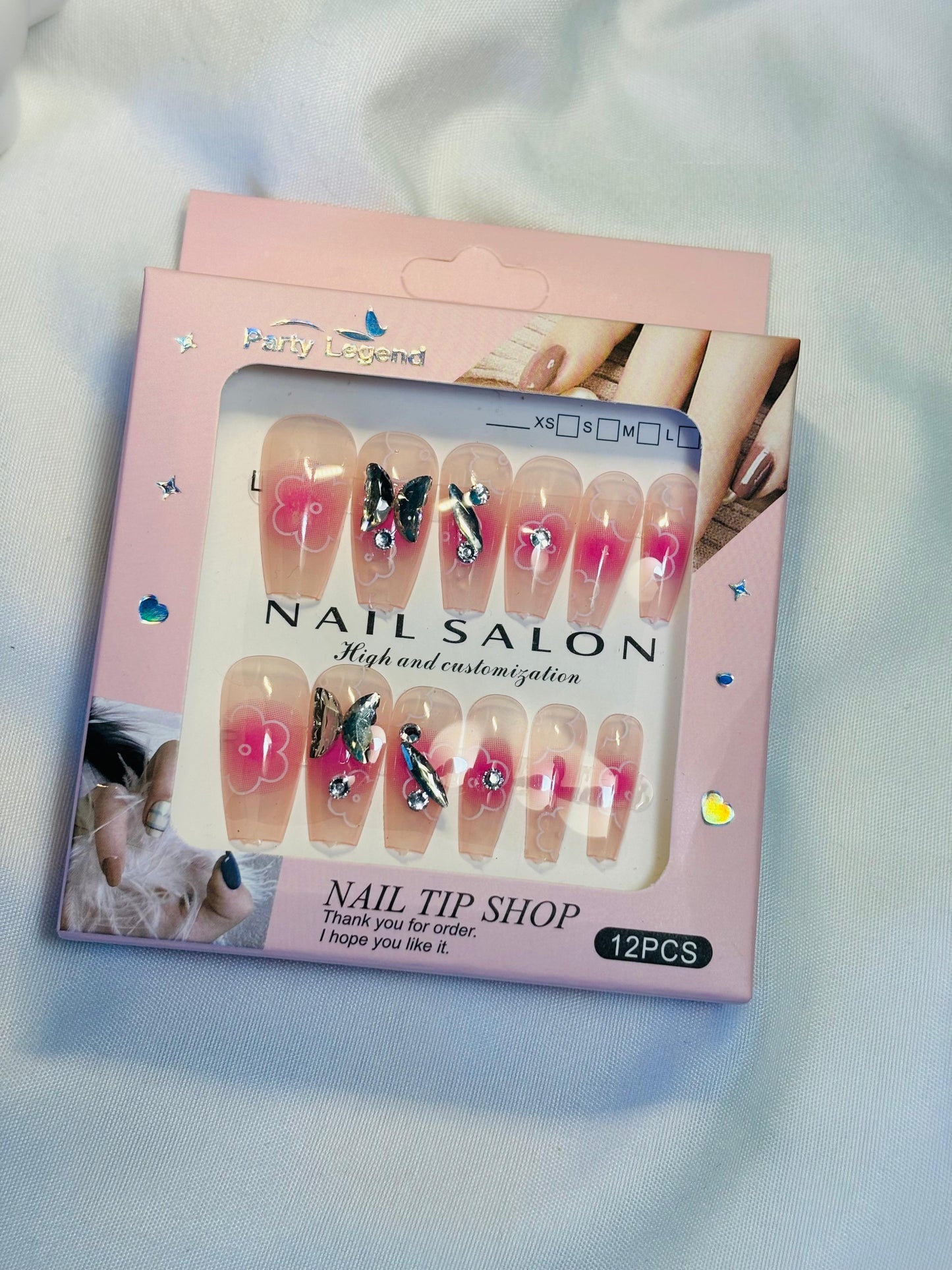 Amora Premium Press-On Fake Nails set box front view

Close-up of press-on nails decorative designs in packaging

Press-on nails box with pink border and branding visible

Display of nail tips floral & rhinestone designs in set

Press-on nails packaging on light background showing full set

Box of artificial nail tips with bold designs close-up

Press-on nail set styled in packaging “Nail Salon” view