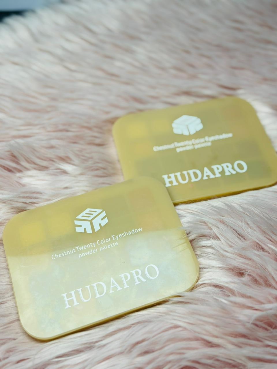 Two yellowHUDAPRO eyeshadow pans on a pink fur background