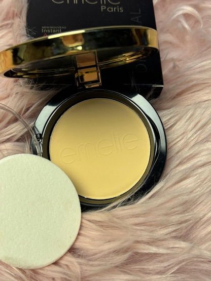 "Open Emelie Paris compact powder with a soft yellow-toned pan, black and gold packaging, and a round makeup sponge placed on a pink fur background."