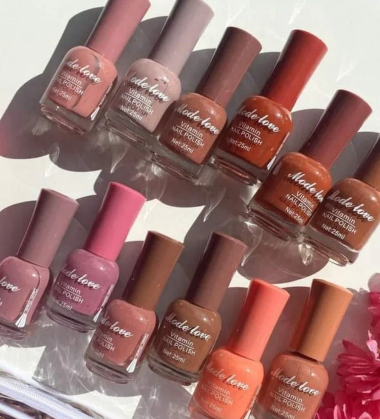 : A set of “Made Love” Vitamin Nail Polishes in various nude, brown, peach, and pink tones arranged neatly in sunlight.