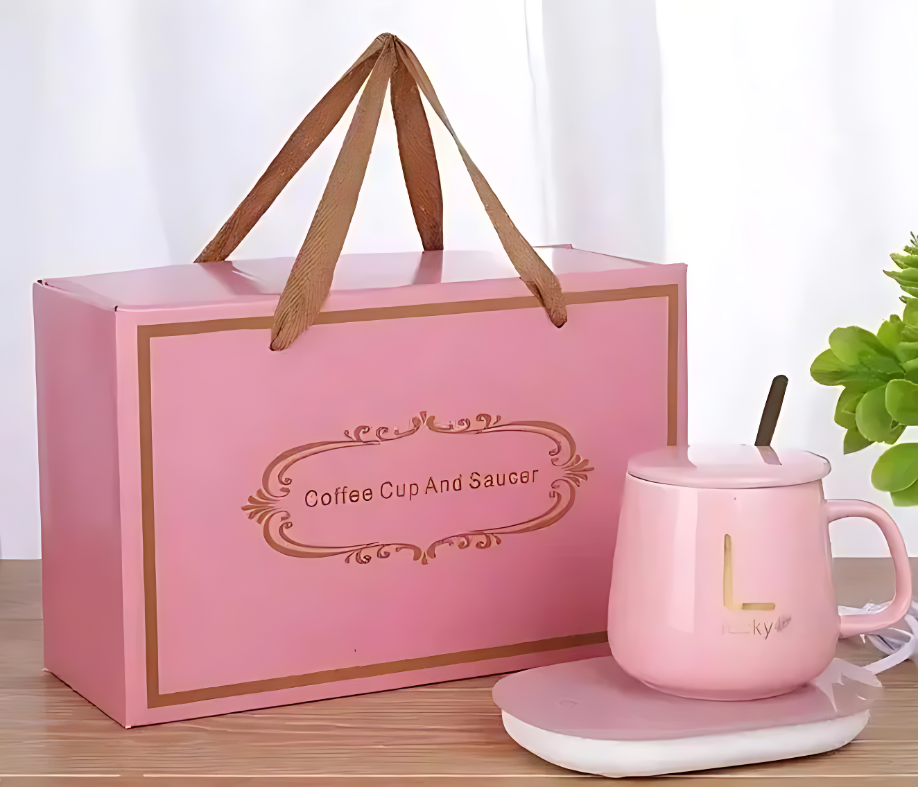 Pink coffee cup and saucer set with matching box on a wooden surface.