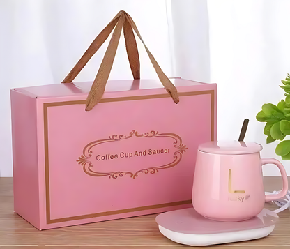 Pink coffee cup and saucer set with matching box on a wooden surface.