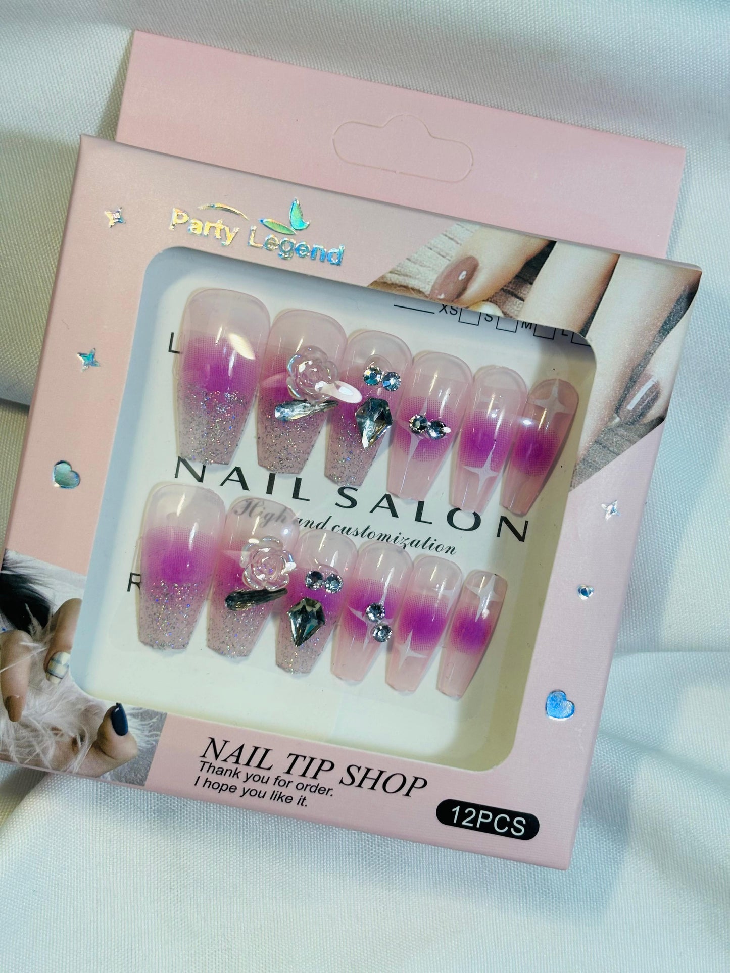 Amora Premium Press-On Fake Nails set box front view

Close-up of press-on nails decorative designs in packaging

Press-on nails box with pink border and branding visible

Display of nail tips floral & rhinestone designs in set

Press-on nails packaging on light background showing full set

Box of artificial nail tips with bold designs close-up

Press-on nail set styled in packaging “Nail Salon” view