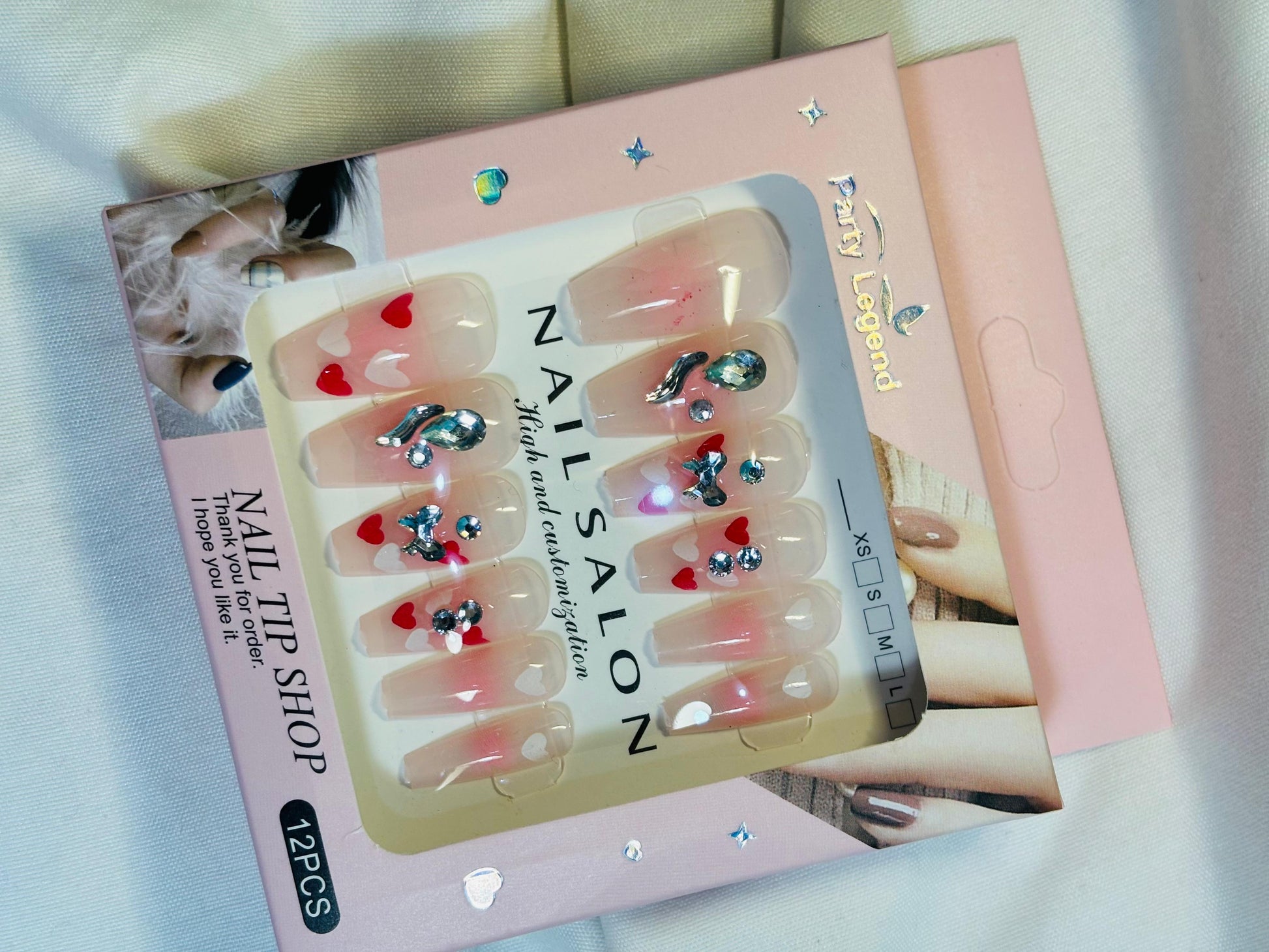 Amora Premium Press-On Fake Nails set box front view

Close-up of press-on nails decorative designs in packaging

Press-on nails box with pink border and branding visible

Display of nail tips floral & rhinestone designs in set

Press-on nails packaging on light background showing full set

Box of artificial nail tips with bold designs close-up

Press-on nail set styled in packaging “Nail Salon” view