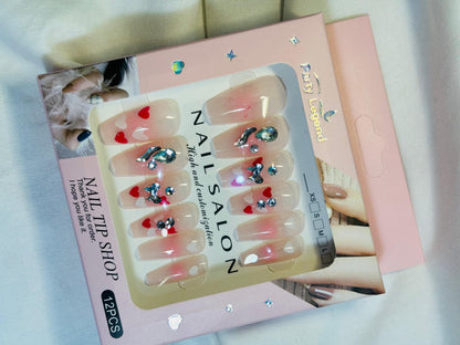 Amora Premium Press-On Fake Nails set box front view

Close-up of press-on nails decorative designs in packaging

Press-on nails box with pink border and branding visible

Display of nail tips floral & rhinestone designs in set

Press-on nails packaging on light background showing full set

Box of artificial nail tips with bold designs close-up

Press-on nail set styled in packaging “Nail Salon” view