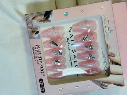 Amora Premium Press-On Fake Nails set box front view

Close-up of press-on nails decorative designs in packaging

Press-on nails box with pink border and branding visible

Display of nail tips floral & rhinestone designs in set

Press-on nails packaging on light background showing full set

Box of artificial nail tips with bold designs close-up

Press-on nail set styled in packaging “Nail Salon” view