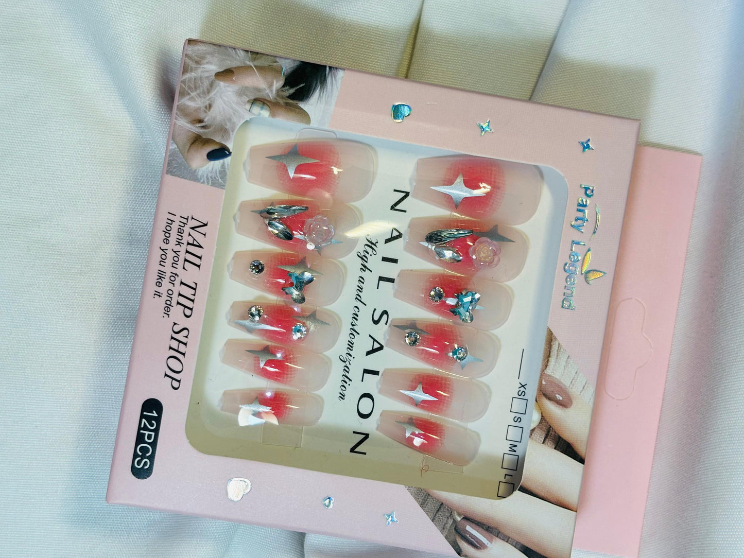 Amora Premium Press-On Fake Nails set box front view

Close-up of press-on nails decorative designs in packaging

Press-on nails box with pink border and branding visible

Display of nail tips floral & rhinestone designs in set

Press-on nails packaging on light background showing full set

Box of artificial nail tips with bold designs close-up

Press-on nail set styled in packaging “Nail Salon” view