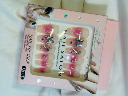 Amora Premium Press-On Fake Nails set box front view

Close-up of press-on nails decorative designs in packaging

Press-on nails box with pink border and branding visible

Display of nail tips floral & rhinestone designs in set

Press-on nails packaging on light background showing full set

Box of artificial nail tips with bold designs close-up

Press-on nail set styled in packaging “Nail Salon” view
