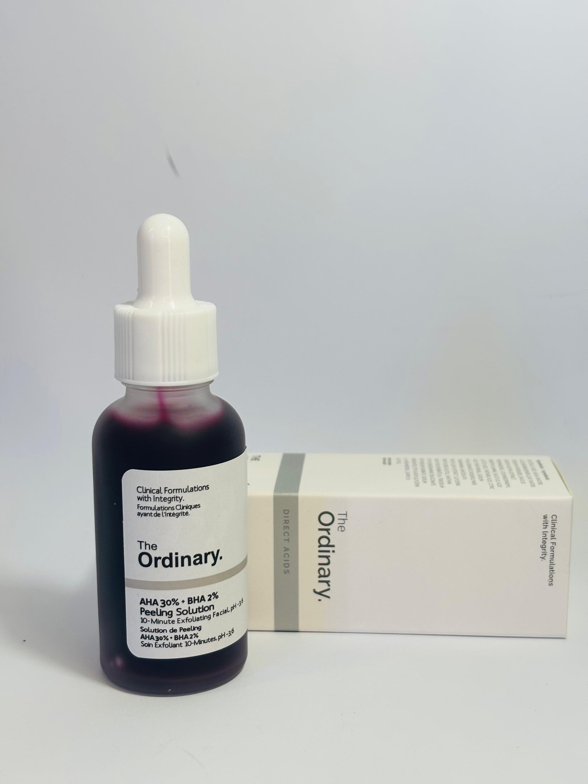 The Ordinary AHA 30% + BHA 2% peeling solution placed upright beside its original packaging box on a plain white background, showing product labeling clearly.