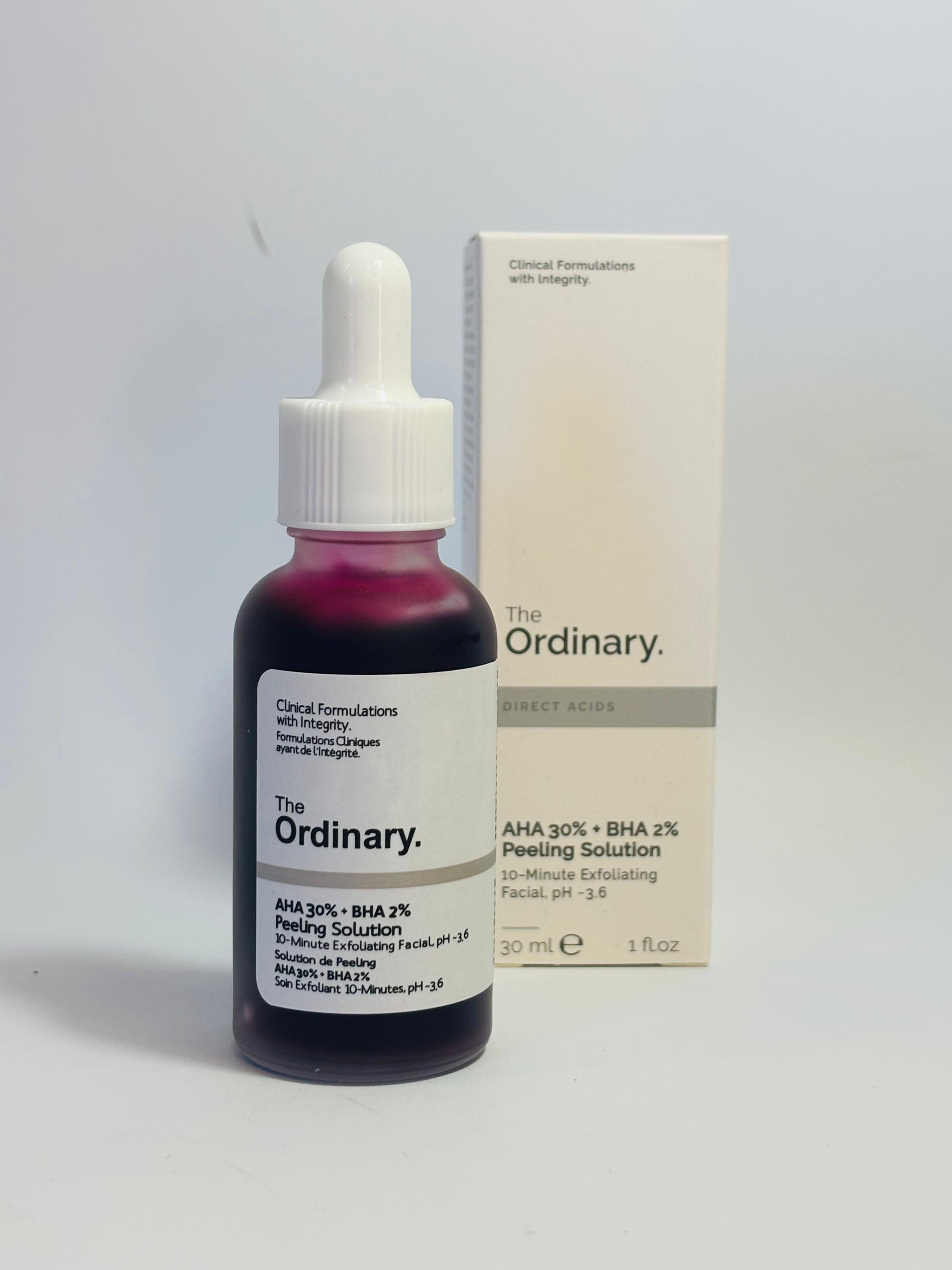 The Ordinary skincare solution bottle with dropper and packaging on a light gray background