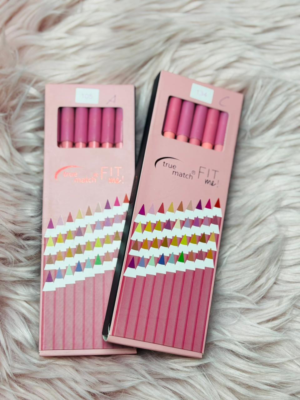 Pink True Match Fit Me pencil set boxes displayed on a soft fur background, showing multiple lip and eye pencils inside the packaging.
