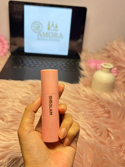SHEGLAM soft pink liquid blush held in a hand with an Amora Mega Store screen in the background.